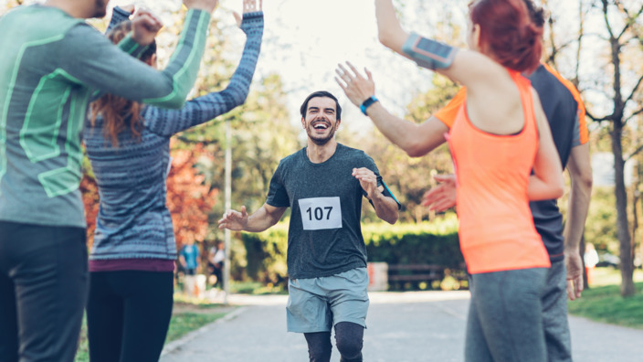 Jogger läuft durch klatschende Läufergruppe ins Ziel