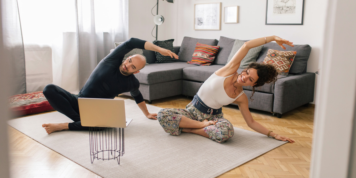 Mann und Frau machen Yoga im Wohnzimmer
