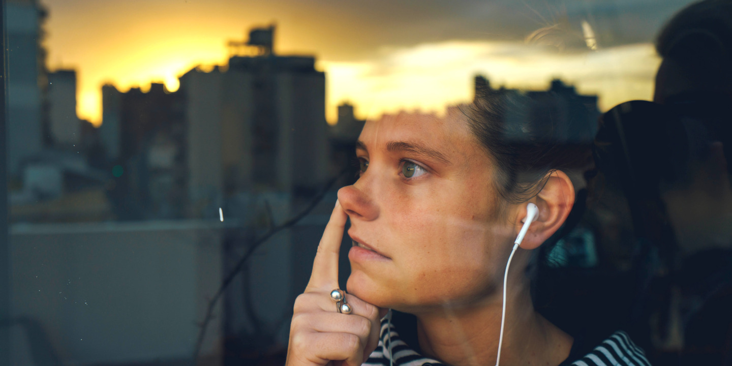 Junge Frau popelt nachdenklich am Fenster in der Nase