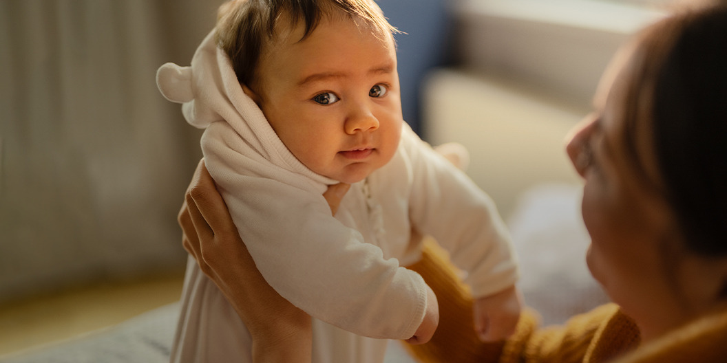 Frau hebt Baby im Strampler hoch