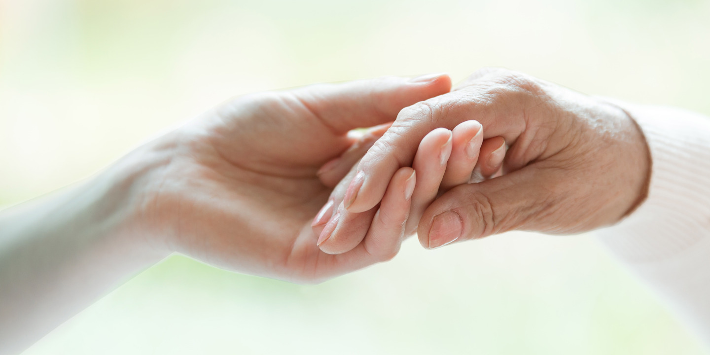 Eine Hand hält die Hand eines Palliativpatienten.