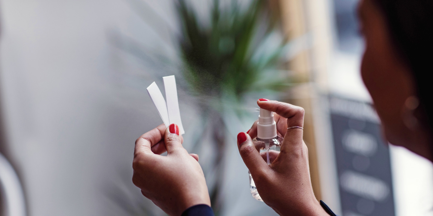 Frau sprüht Parfum auf zwei Teststreifen