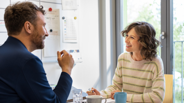 Frau und Mann unterhalten sich am Besprechungstisch