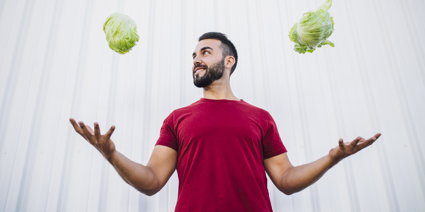 Sportlicher Mann wirft in jeder Hand einen Salat in die Luft