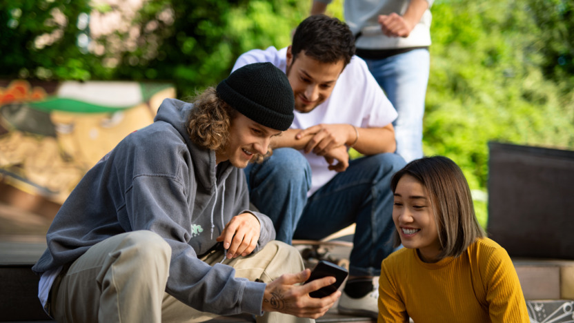 Drei Jugendliche, die lachend auf ein Handy schauen