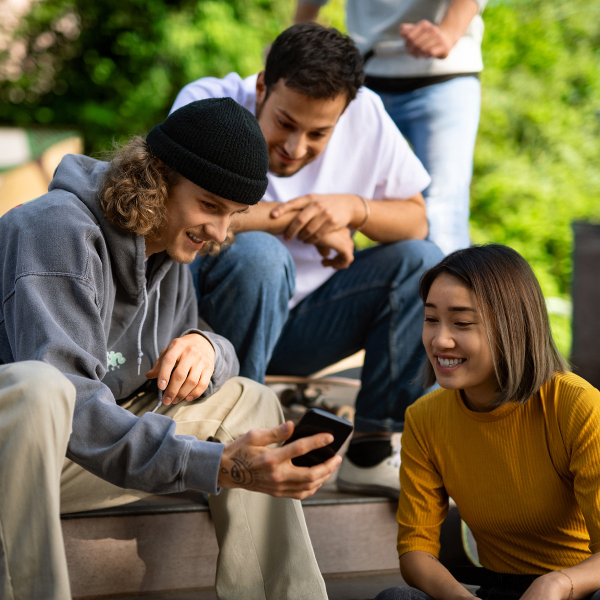 Jugendliche sitzen zusammen und schauen auf ein Handy-Display
