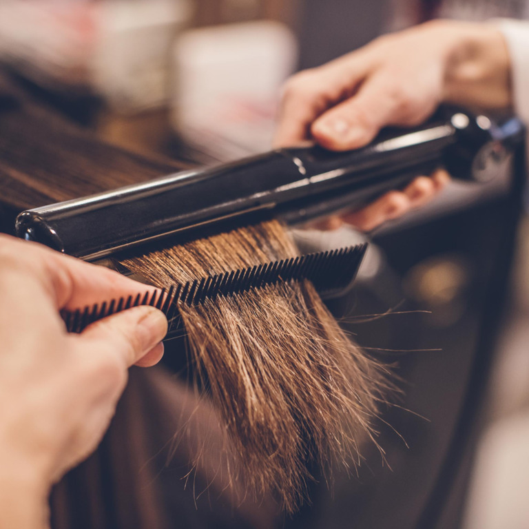 Blinde Friseurin beim Glätten von Haaren