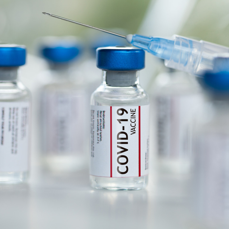Fläschchen mit Impfstoff gegen das Coronavirus SARS-CoV-2 und Spritzen.