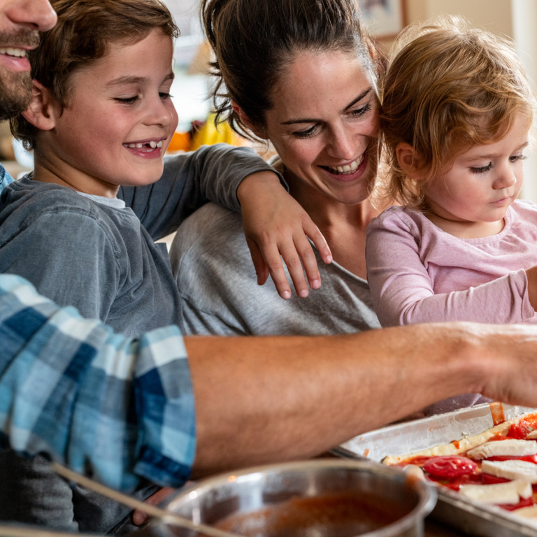 Eltern kochen mit ihrem kleinen Sohn und ihrer kleinen Tochter in der Küche.