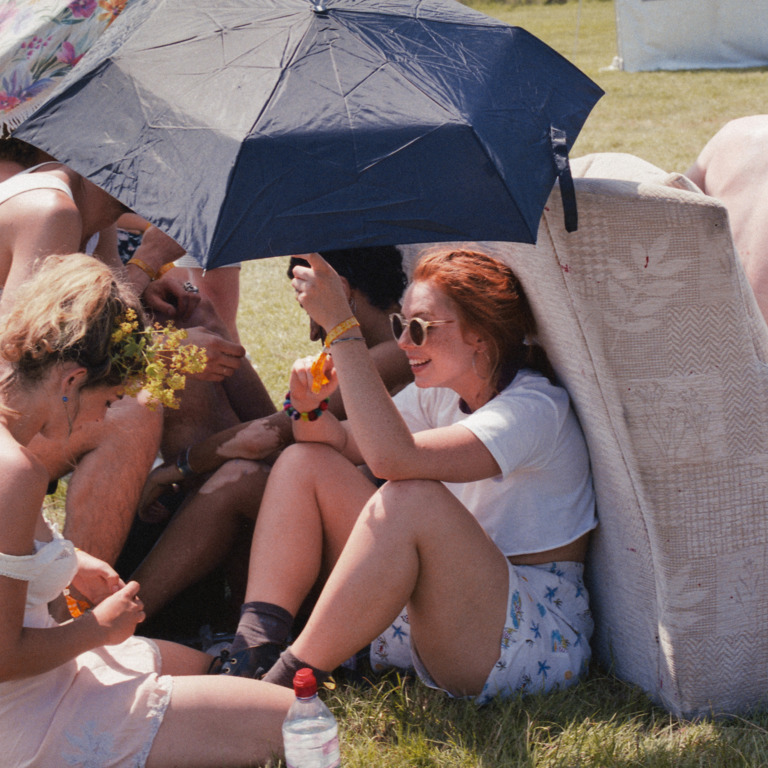 Junge Menschen mit Schirmen beim Zelten auf Festival