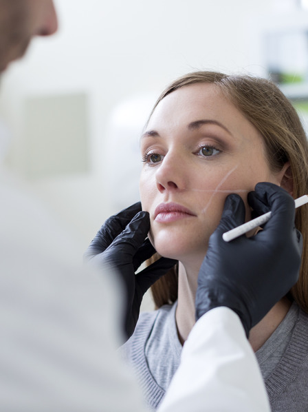 Frau wird von einem Arzt für eine Schönheitsoperation im Gesicht vorbereitet.