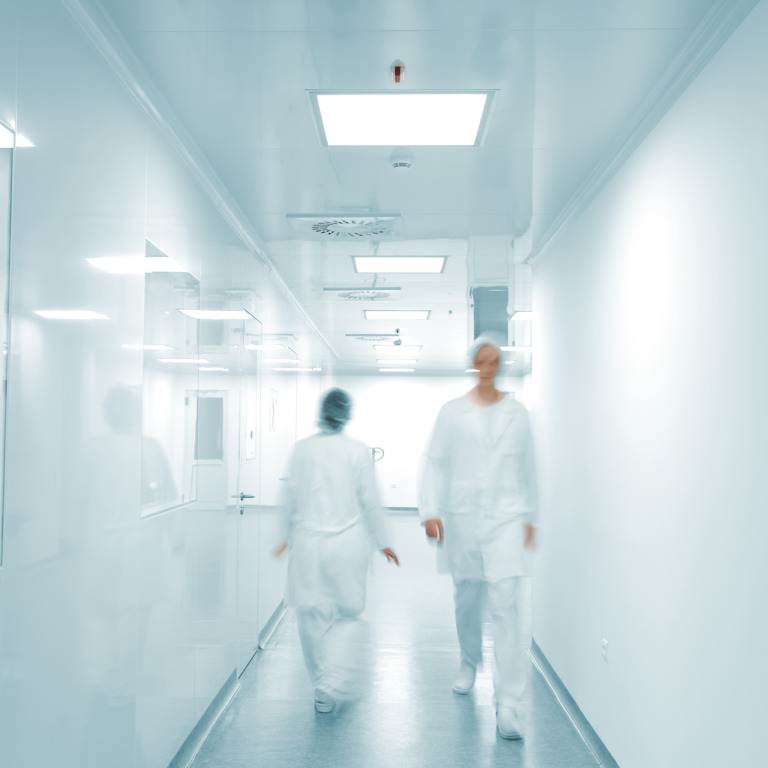 Flur im Krankenhaus, Personal in Krankenhaus-Bekleidung läuft über den Flur