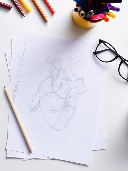 Zeichnung eines Herzens auf einem Blatt Papier liegt auf einem Schreibtisch.
