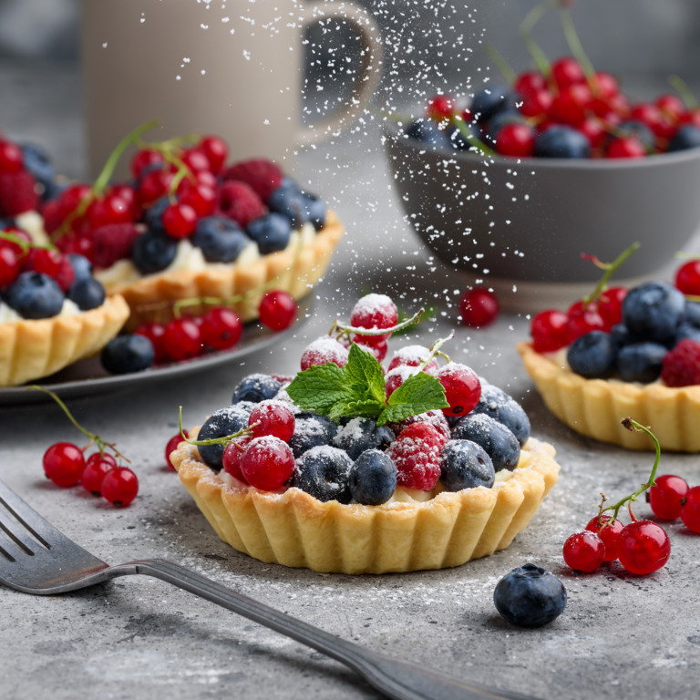 Ein veganes Tartelette mit Himbeeren, Heidelbeeren und Pfefferminzblättern.
