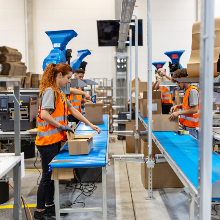 Mehrere Personen arbeiten in Paketverpackungsanlage