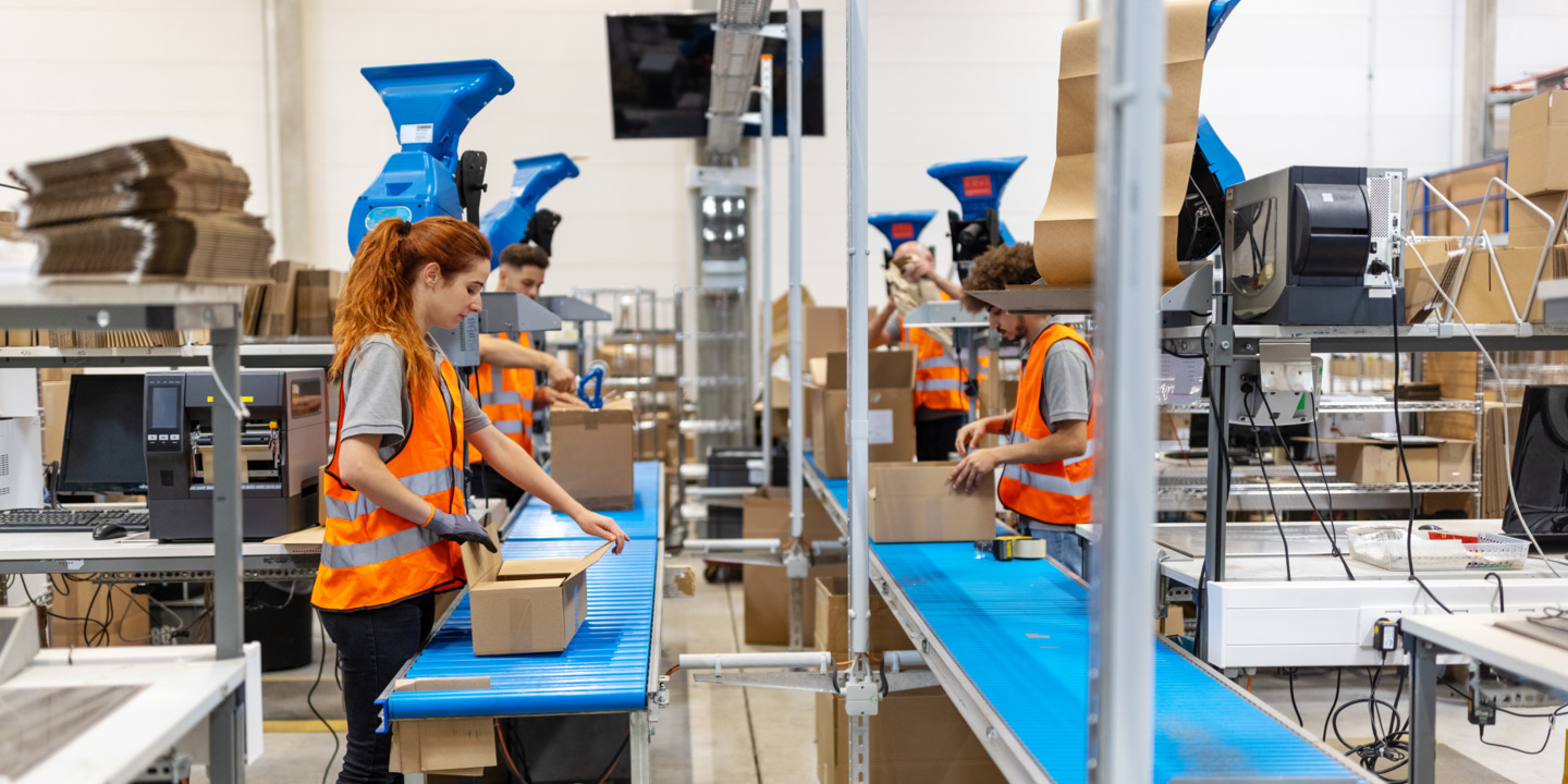 Mehrere Personen arbeiten in Paketverpackungsanlage