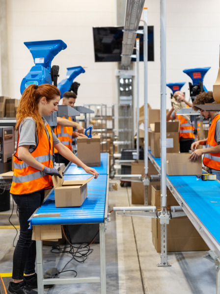 Mehrere Personen arbeiten in Paketverpackungsanlage