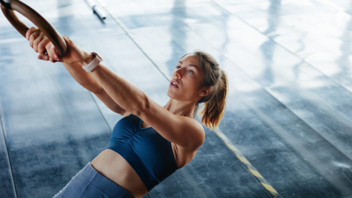 Frau trainiert im Fitnessstudio an Ringen
