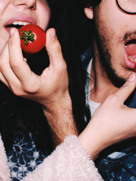 Eine Frau und ein Mann stekcen sich gegenseitig Tomaten in den Mund.