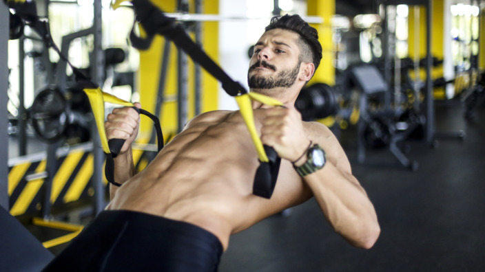 Person trainiert an Gerät im Fitnessstudio