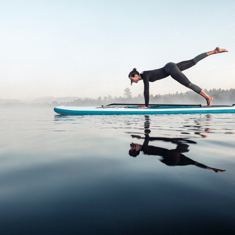 Frau macht Yoga auf Stand-up Paddleboard