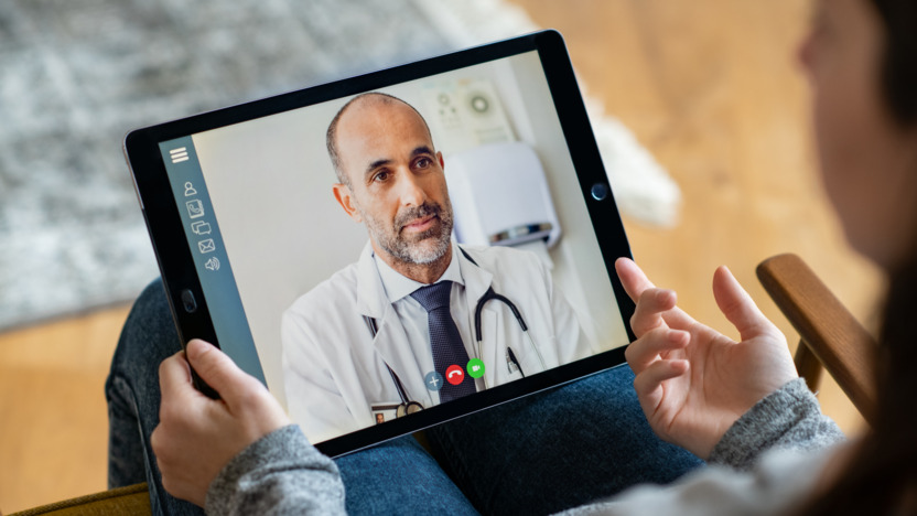 Arzt im weißen Kittel in einem Videoanruf auf einem Tablet
