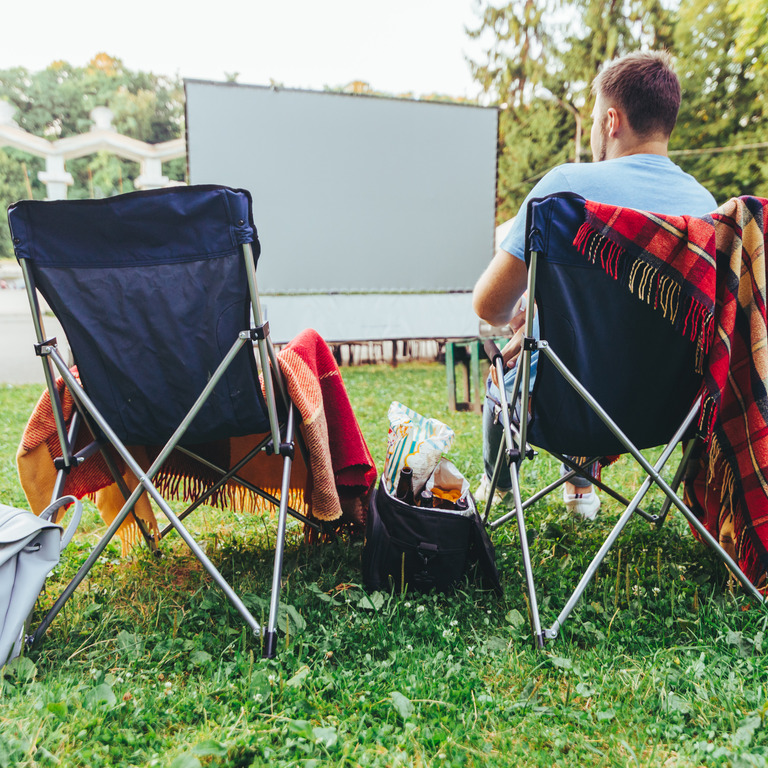 Mann sitzt auf einem Campingstuhl im Open Air Kino