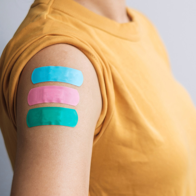 Arm einer Frau mit drei Impf-Pflastern