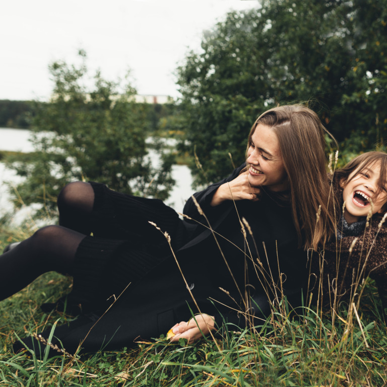 Frau und Kind spielen auf Wiese am See