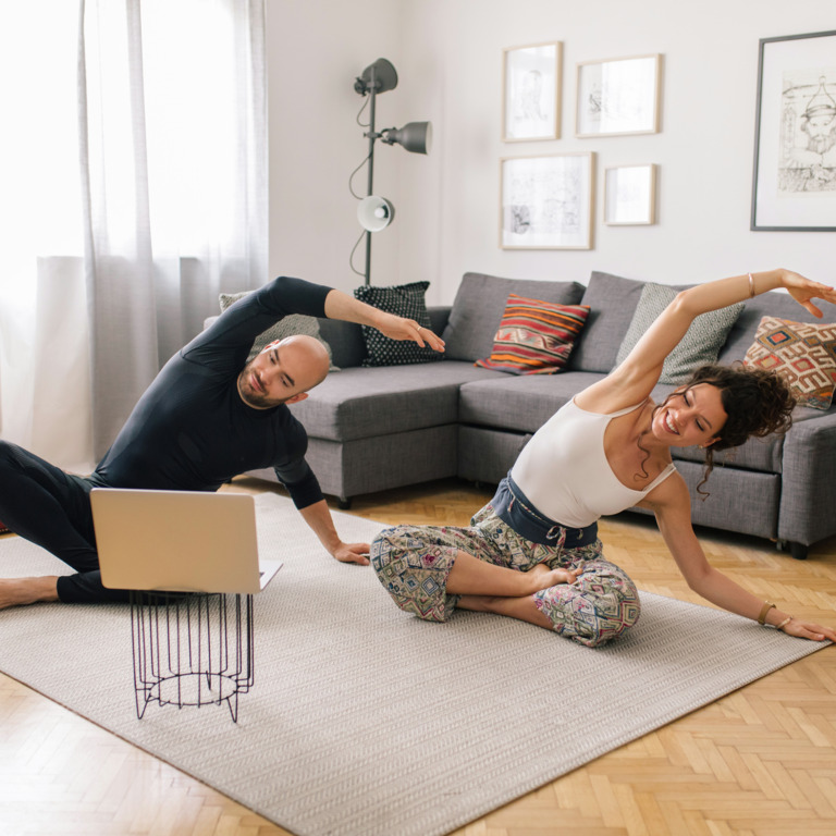 Paar macht Sport im Wohnzimmer vor dem Laptop