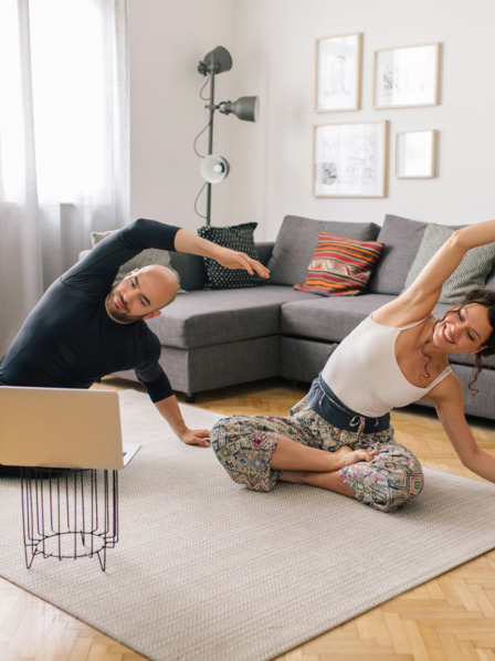 Paar macht Sport im Wohnzimmer vor dem Laptop