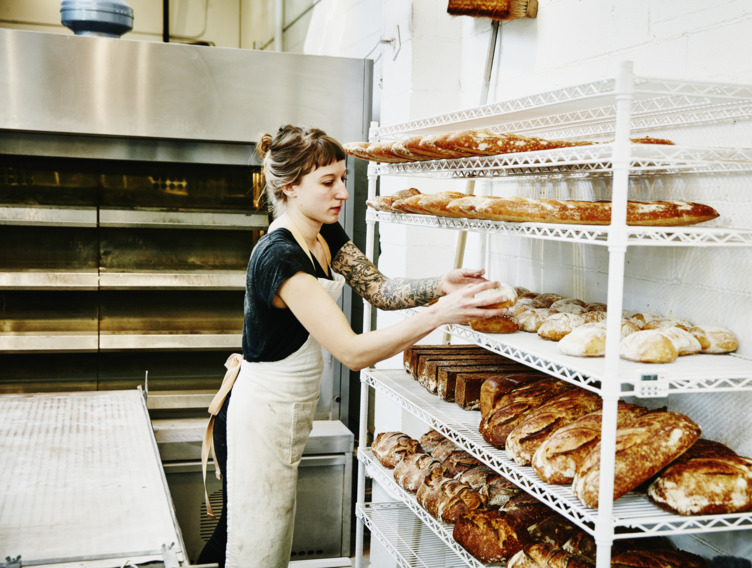 Junge Bäckerin sortiert Brot in der Backstube