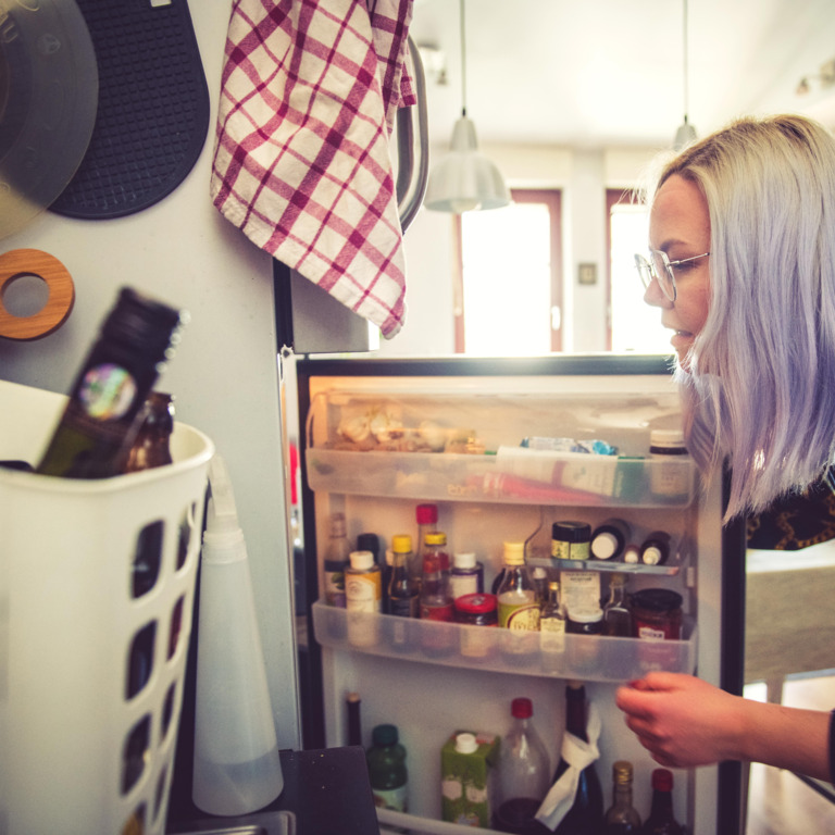 Frau schaut in den Kühlschrank