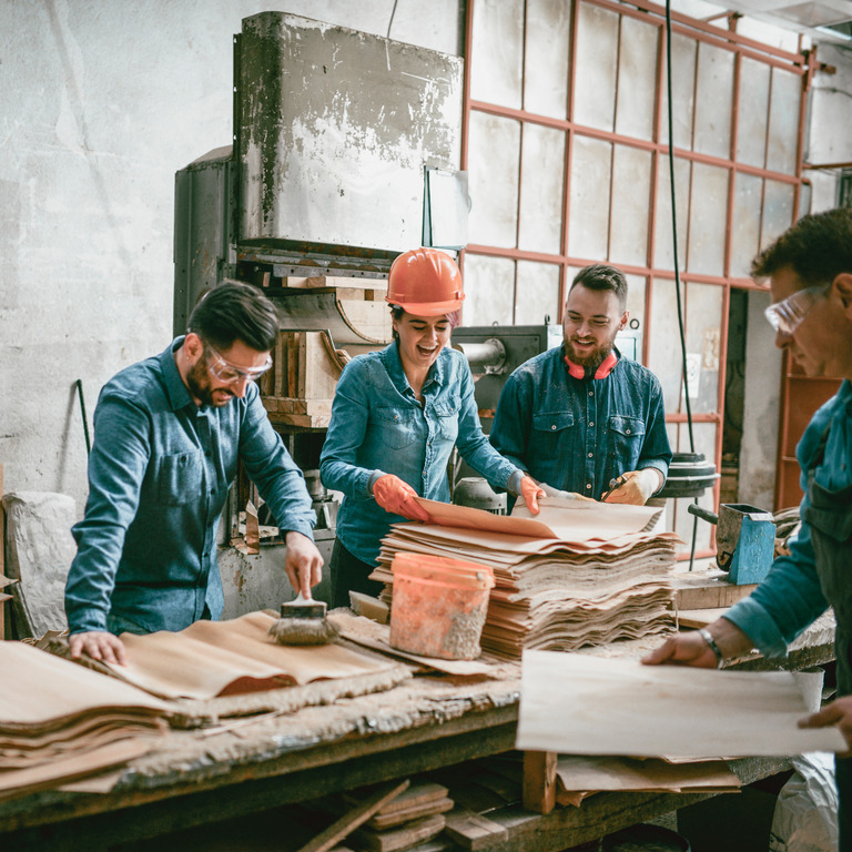 Vier Handwerker lachen zusammen in der Werkstatt
