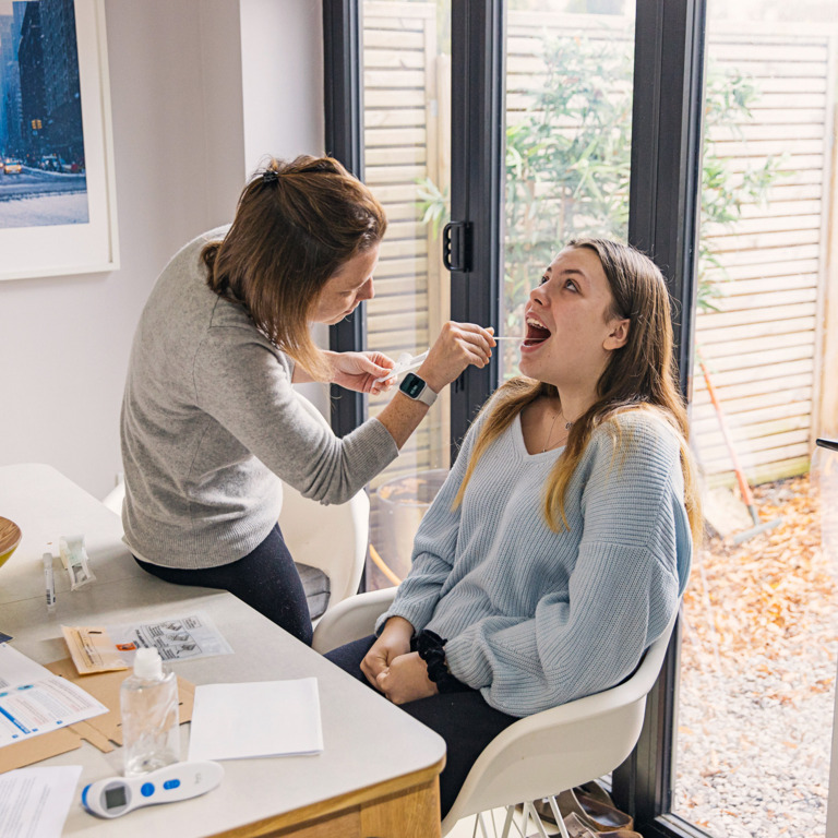 Frau steckt anderer Frau Corona-Test-Stäbchen in den Mund