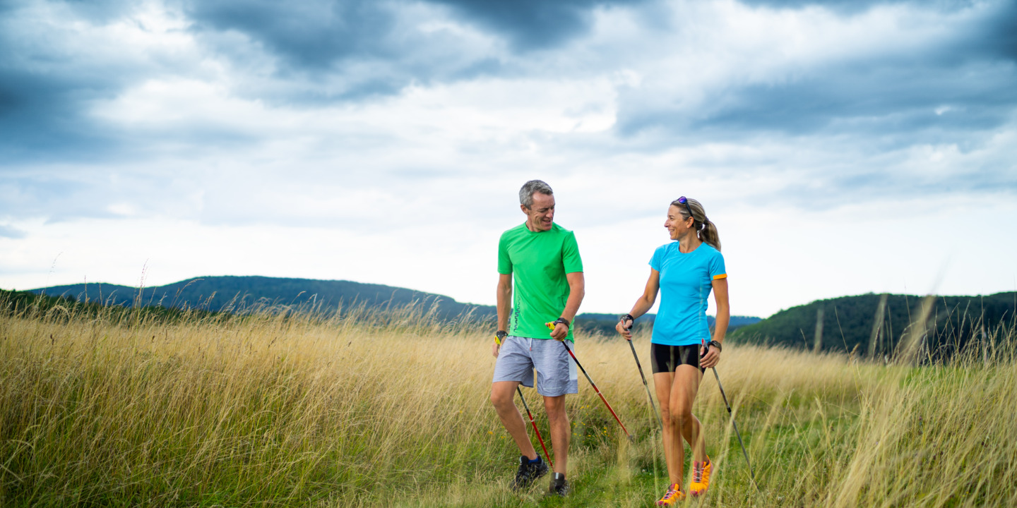 Mann und Frau machen Nordic Walking auf einem Feldweg