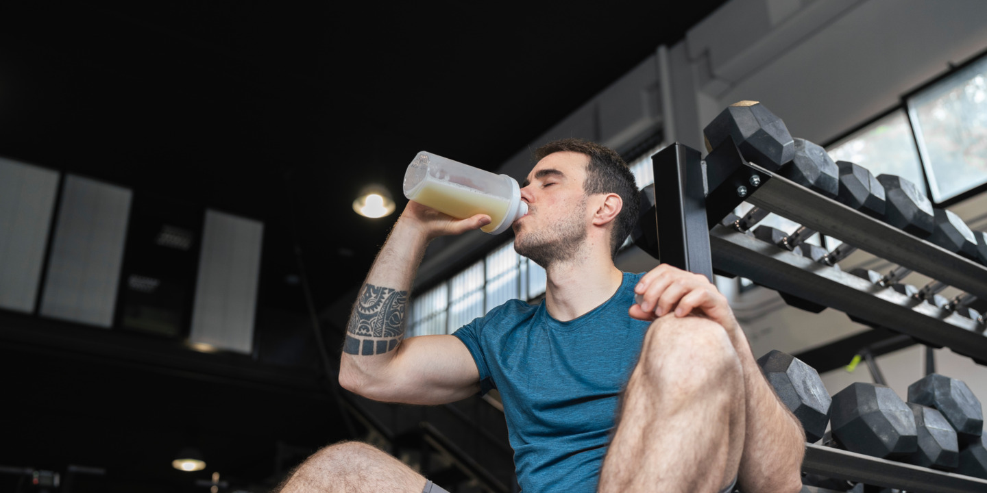 Mann in Sportkleidung trinkt Proteinshake