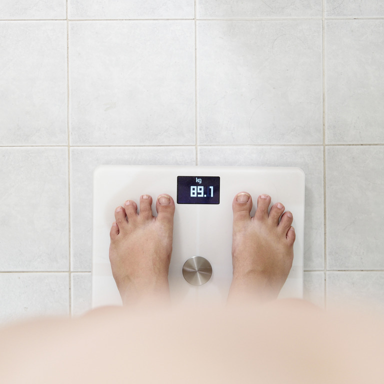 Eine Person steht auf einer Waage, die 89,1Kilogramm anzeigt – noch Normalgewicht oder schon Übergewicht?