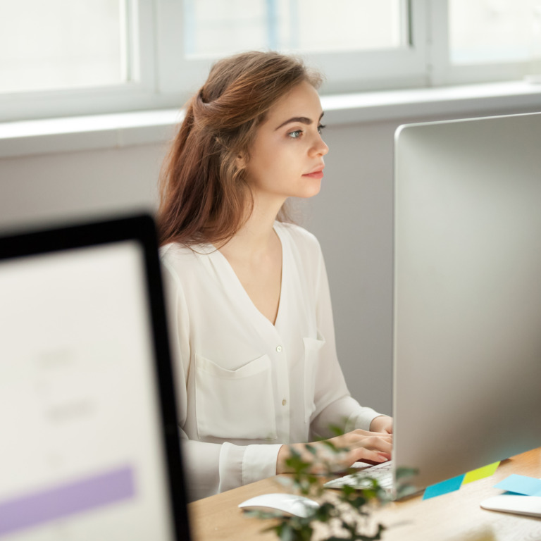 Junge Frau sitzt vor Computerbildschirm