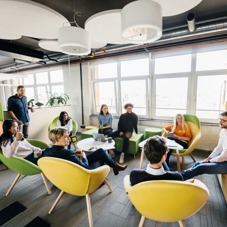 Menschen sitzen in einer Runde im offenen Büro zusammen