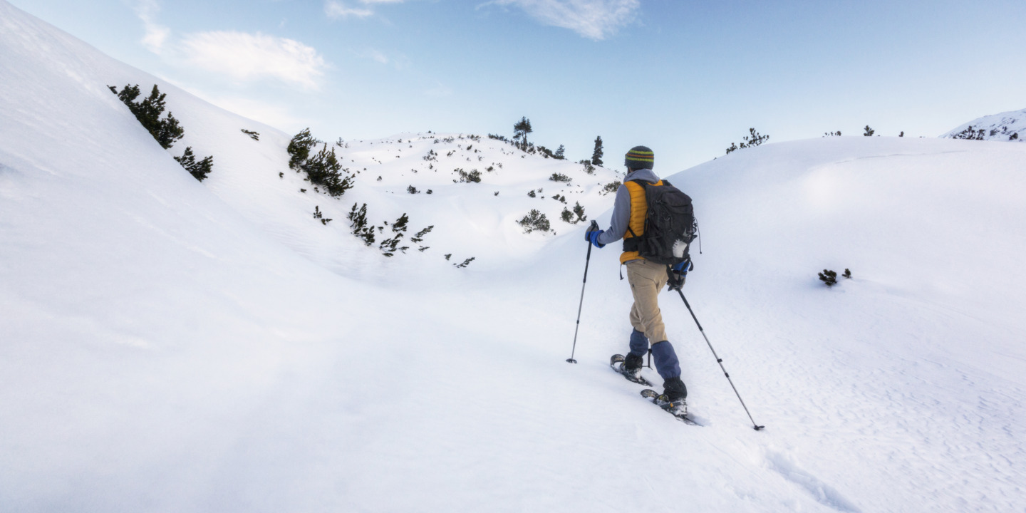 Mann auf Schneeschuhen wandert durch eine Schneelandschaft