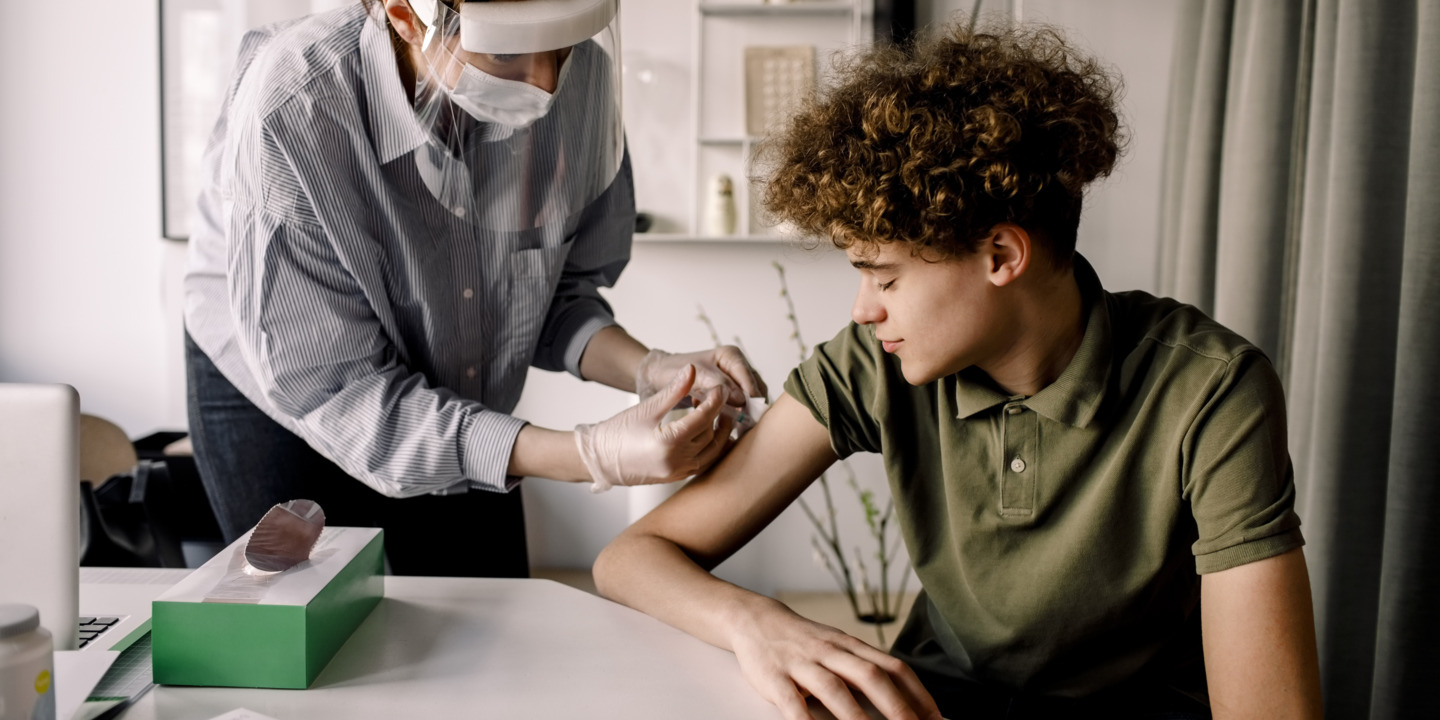 Junger Mann bekommt von seiner Ärztin eine HPV Impfung