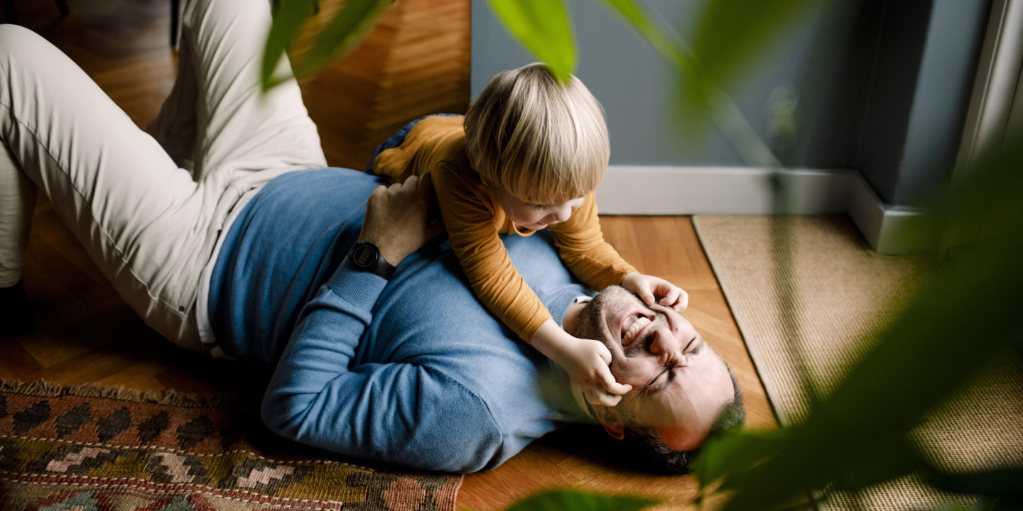 Vater und Sohn albern auf dem Boden herum