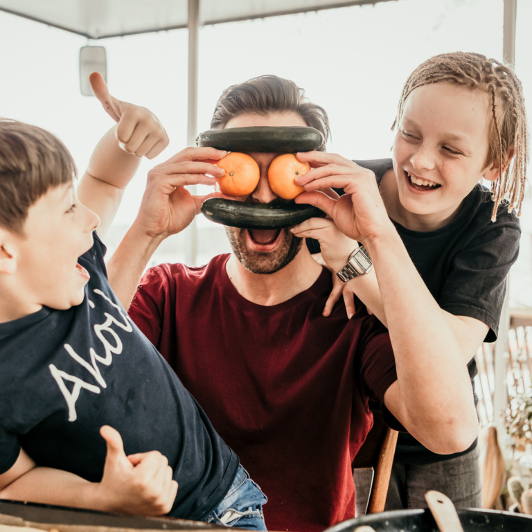 Mann und Kinder albern beim Kochen herum