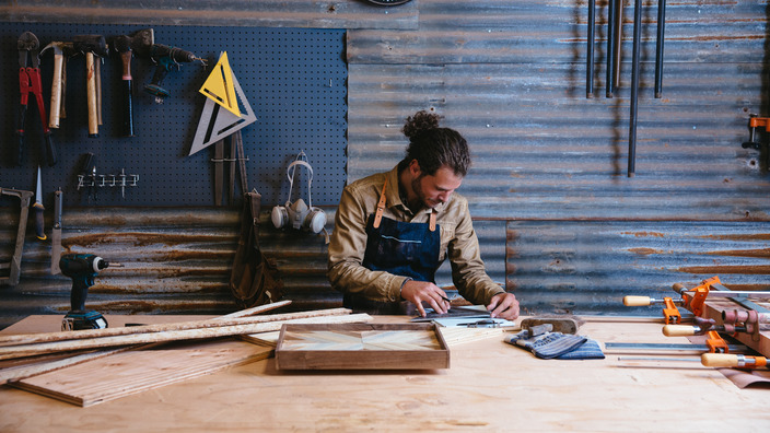 Selbstständiger Handwerker arbeitet an Werkbank in seiner Werkstatt