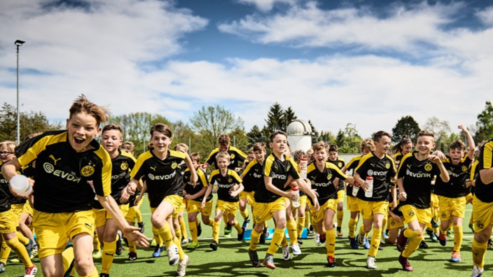 Junge Fußballer im BVB-Outfit laufen über den Rasen