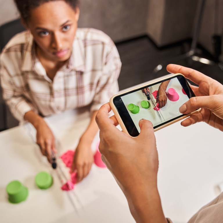 Frau filmt mit Smartphone Bloggerin, die kinetischen Sand schneidet