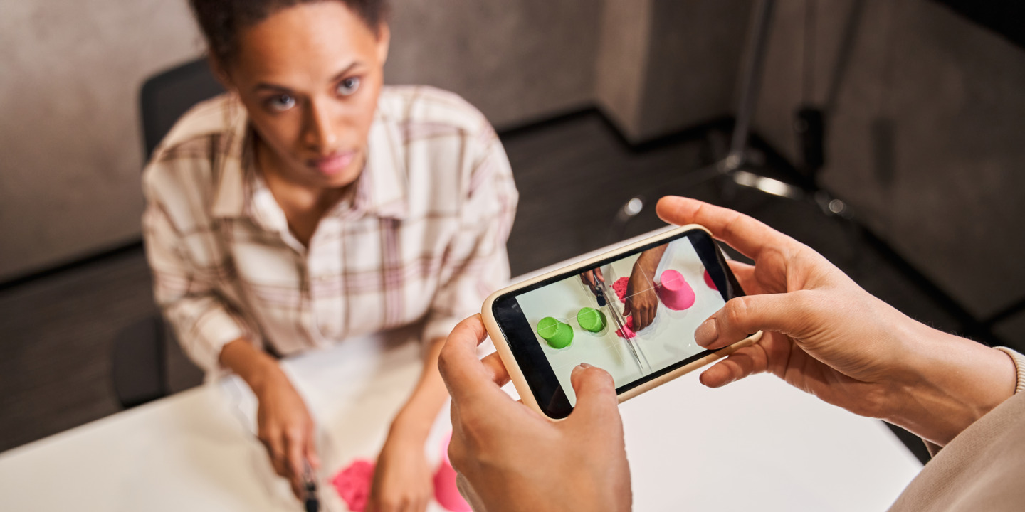 Frau filmt mit Smartphone Bloggerin, die kinetischen Sand schneidet