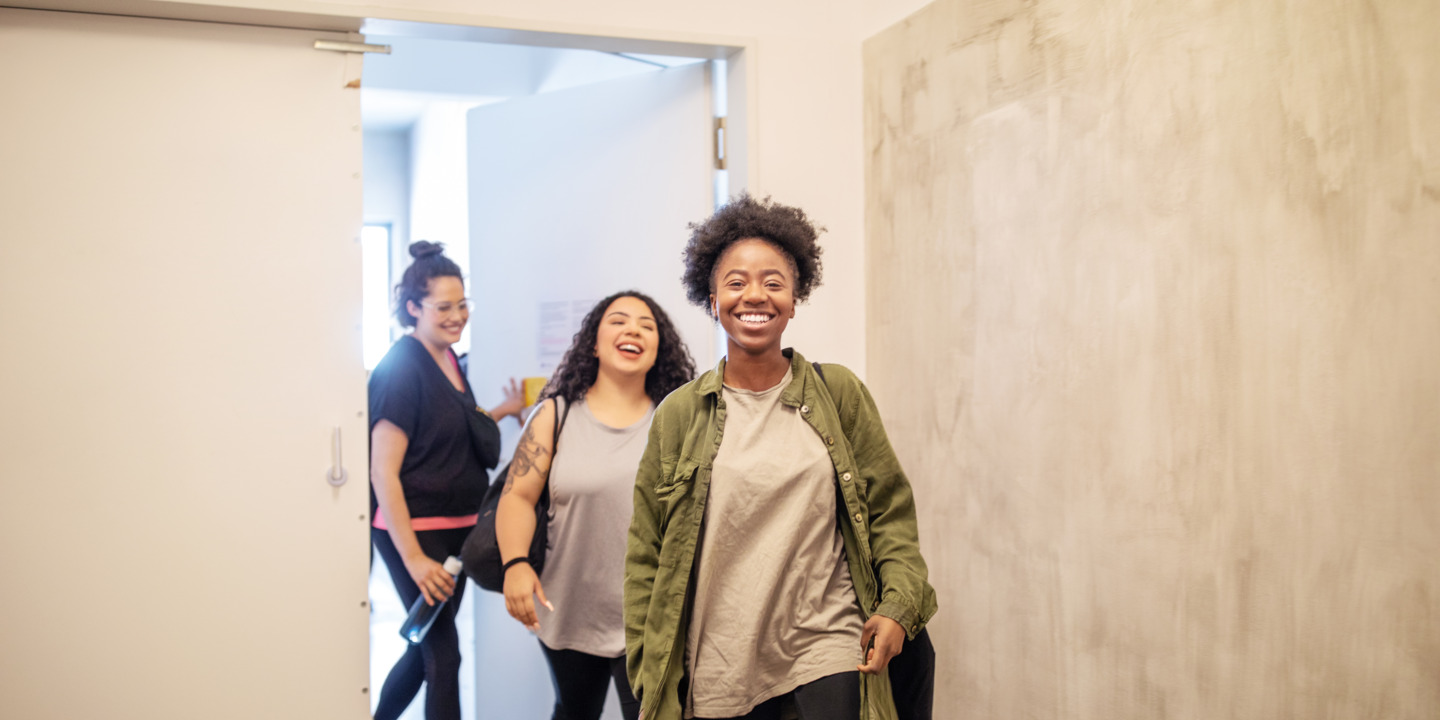 Junge Frauen verlassen lachend zum Feierabend das Büro