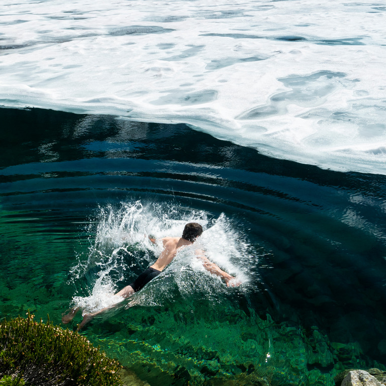 Mann schwimmt im von Eis bedecktem Wasser